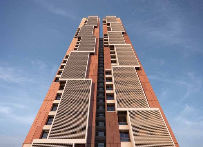 A tower at Myscape Songs of the Sun seen from the base, showing the louvred screens and the terracotta banding of the façade.